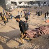 Palestinians carry away a covered body as people gather to inspect the damage at Gaza's Al-Shifa hospital after the Israeli military withdrew from the complex housing the hospital after a two week siege.