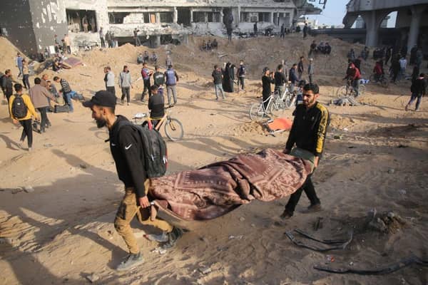 Palestinians carry away a covered body as people gather to inspect the damage at Gaza's Al-Shifa hospital after the Israeli military withdrew from the complex housing the hospital after a two week siege.