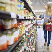 A woman buys products in a supermarket food aisle