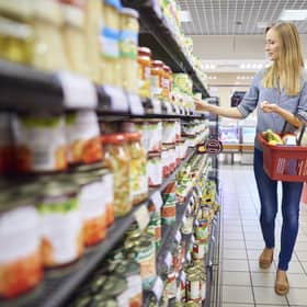 A woman buys products in a supermarket food aisle