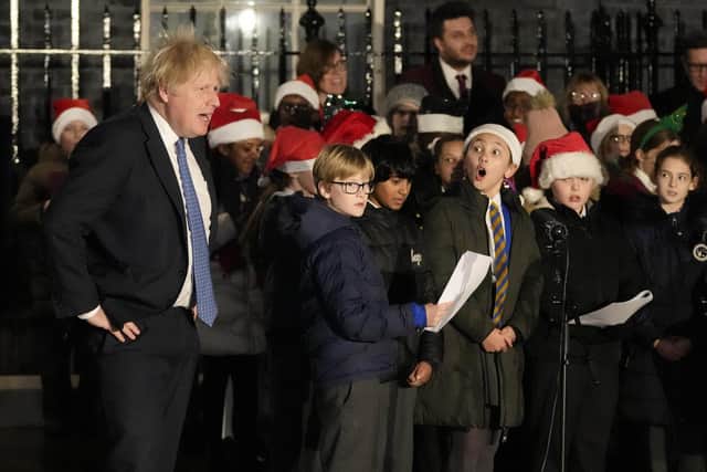 Britain's Prime Minister Boris Johnson listens to a children's choir sing during the ceremony to switch on the Downing Street Christmas tree lights in London. Picture: AP Photo/Frank Augstein