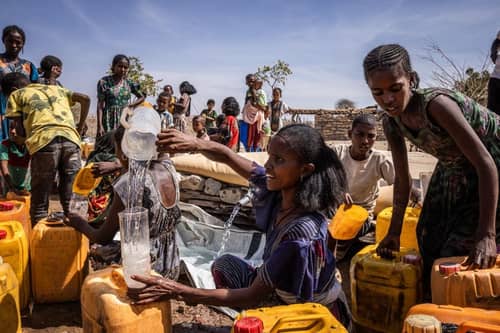 People fill jerry cans with water at a Red Cross water distribution in the Tigray region of Ethiopia. More than 20 million Ethiopians are in need of food aid, according to estimates from the UN's Office for the Coordination of Humanitarian Affairs (UNOCHA).