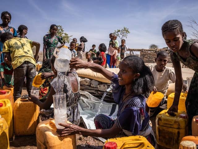 People fill jerry cans with water at a Red Cross water distribution in the Tigray region of Ethiopia. More than 20 million Ethiopians are in need of food aid, according to estimates from the UN's Office for the Coordination of Humanitarian Affairs (UNOCHA).