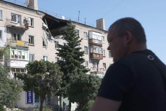 A man walks in front of damaged residential building on a street of the town of Lysychansk.