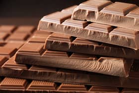 Multiple chocolate bars are piled on top of one another against a black background.