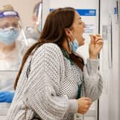 A woman uses a swab to take a sample from her mouth at a NHS Test and Trace Covid-19 testing unit at the Civic Centre in Uxbridge, Hillingdon, west London on May 25, 2021. Photo by ADRIAN DENNIS/AFP via Getty Images