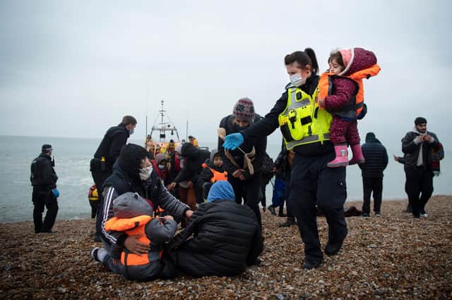 A member of the UK Border Force, right, helps child migrants on a beach at Dungeness, south-east England (Picture: Ben Stansall/AFP via Getty Images)