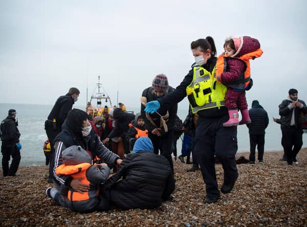 A member of the UK Border Force, right, helps child migrants on a beach at Dungeness, south-east England (Picture: Ben Stansall/AFP via Getty Images)
