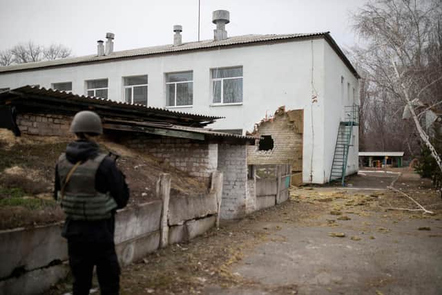 A Ukrainian soldier stands next to a damaged wall after the reported shelling of a kindergarten in the settlement of Stanytsia Luhanska. (Photo by Aleksey Filippov / AFP) (Photo by ALEKSEY FILIPPOV/AFP via Getty Images)