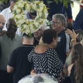FIFA President Gianni Infantino, left, takes a selfie with Lima, a former Santos soccer player, and others, during the wake of the late Brazilian soccer great Pele, who lies in state, below, at Vila Belmiro stadium in Santos, Brazil, Monday, Jan. 2, 2023. (AP Photo/Andre Penner)