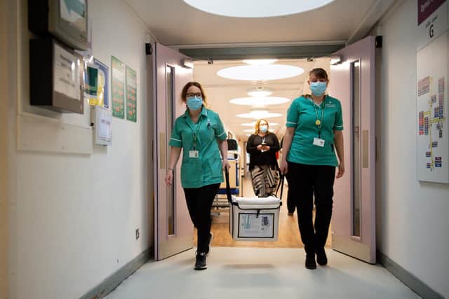 Pharmacists transport a cooler containing the Moderna vaccine, at the West Wales General Hospital in Carmarthen.