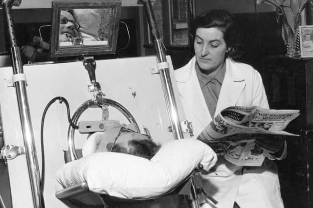 Kenneth Evans, a patient in an iron lung in 1949, is read the news by his wife (Picture: Keystone Features/Getty Images)