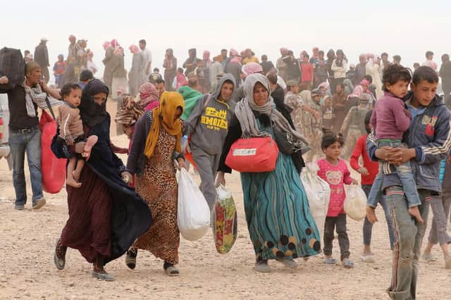 Syrian refugees carry their belongings as they wait to enter Jordanian side of the Hadalat border crossing, a military zone east of the capital Amman, after arriving from Syria       (Photo: KHALIL MAZRAAWI/AFP via Getty Images)