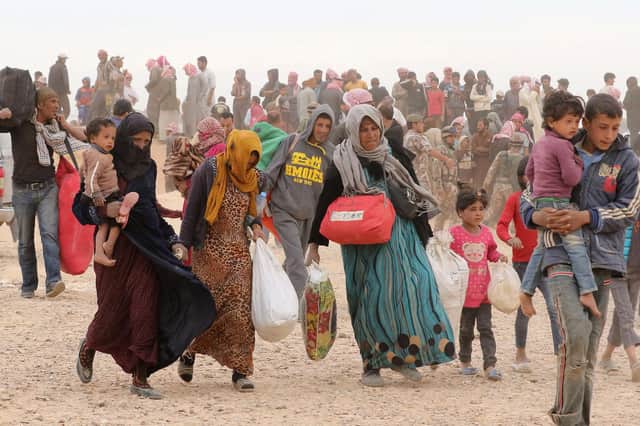 Syrian refugees carry their belongings as they wait to enter Jordanian side of the Hadalat border crossing, a military zone east of the capital Amman, after arriving from Syria (Photo: KHALIL MAZRAAWI/AFP via Getty Images)
