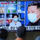 People at a train station watch news reports on a big screen featuring North Korean leader Kim Jong Un as Covid spreads in the country (Picture: Lee Jin-man/AP)