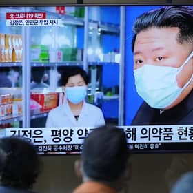 People at a train station watch news reports on a big screen featuring North Korean leader Kim Jong Un as Covid spreads in the country (Picture: Lee Jin-man/AP)