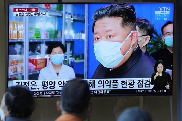 People at a train station watch news reports on a big screen featuring North Korean leader Kim Jong Un as Covid spreads in the country (Picture: Lee Jin-man/AP)