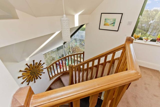 The solid cherry staircase curves past a cantilevered double aspect corner window.