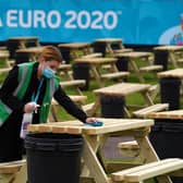 Justine Ralston cleans tables as finishing preparations are made to the UEFA Euro 2020 fan zone at Glasgow Green. Picture: Andrew Milligan/PA Wire