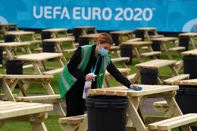 Justine Ralston cleans tables as finishing preparations are made to the UEFA Euro 2020 fan zone at Glasgow Green. Picture: Andrew Milligan/PA Wire