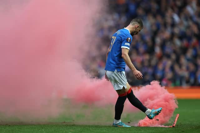 GLASGOW, SCOTLAND - MAY 05: Borna Barisic of Rangers clears a flare from the pitch during the UEFA Europa League Semi Final Leg Two match between Rangers and RB Leipzig at Ibrox Stadium on May 05, 2022 in Glasgow, Scotland. (Photo by Ian MacNicol/Getty Images)