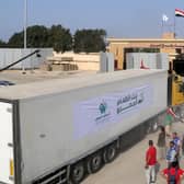 People on the Egyptian side of the Rafah border crossing watch as a convoy of lorries carrying desperately needed humanitarian aid crosses to the Gaza Strip yesterday