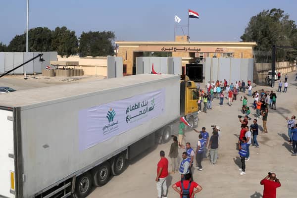 People on the Egyptian side of the Rafah border crossing watch as a convoy of lorries carrying desperately needed humanitarian aid crosses to the Gaza Strip yesterday