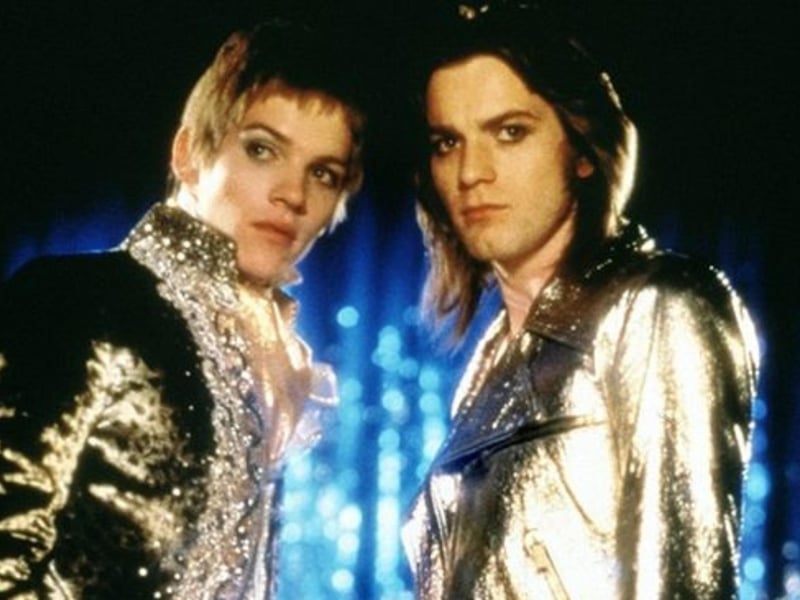 Brian Slade is a Glam Rock star who predicts his own death on stage. After making the prediction, shortly after he fakes his death but is discovered for it being exposed as a fraud.  A former fan tracks down Slade to get answers on his motivations and interviews the rocker's peers along the way.