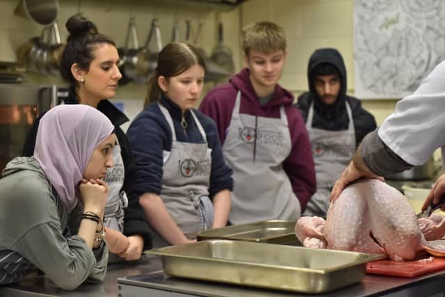 Young people watching turkey butchery demonstration.