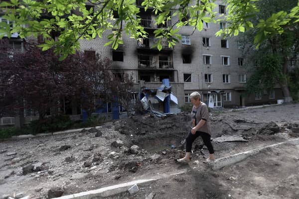 A woman walks past a shell crater in front of a damaged residential building in the town of Siversk, Donetsk region, on June 23, 2022, amid Russia's military invasion launched on Ukraine. -  via Getty Images