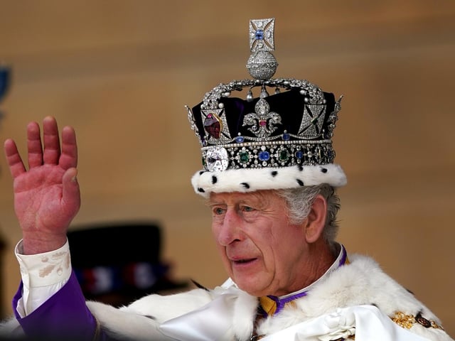 King Charles III receives a royal salute from members of the military in the gardens of Buckingham Place.