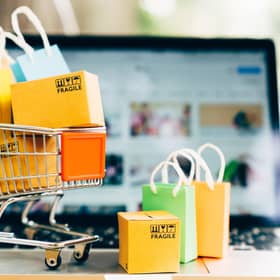 Product package boxes and shopping bag in cart with laptop computer which web store shop on screen for online shopping and delivery concept