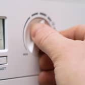 A homeowner turning down the temperature of a gas boiler.