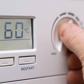 A homeowner turning down the temperature of a gas boiler.