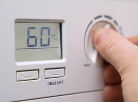 A homeowner turning down the temperature of a gas boiler.