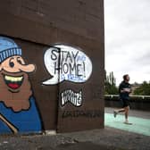 A jogger passes coronavirus-related graffiti. A key SNP figure has been accused of encouraging party branches to apply for Covid support grant funding. Picture: Andrew Milligan/PA Wire