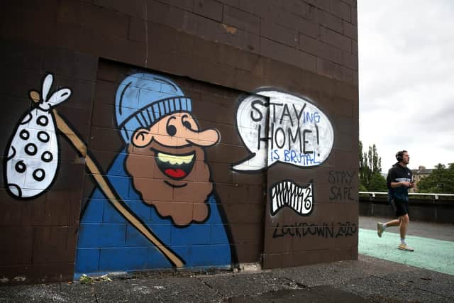 A jogger passes coronavirus-related graffiti. A key SNP figure has been accused of encouraging party branches to apply for Covid support grant funding. Picture: Andrew Milligan/PA Wire