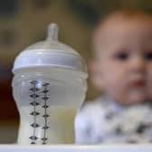 A baby in a high chair looking towards her bottle of milk in the foreground. A new probe into the supply of baby formula milk has been launched by Britain's competition watchdog. Picture: Andrew Matthews/PA Wire