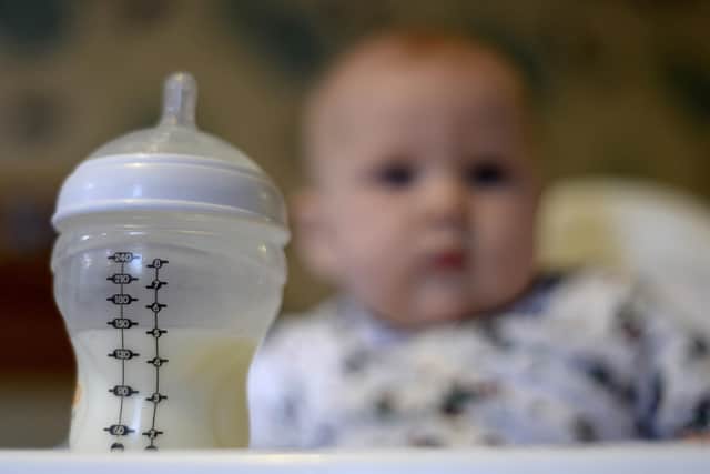 A baby in a high chair looking towards her bottle of milk in the foreground. A new probe into the supply of baby formula milk has been launched by Britain's competition watchdog. Picture: Andrew Matthews/PA Wire