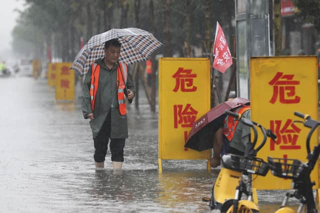 Staff members set up warning signs with the words 'Danger!' at a waterlogged area in Wuzhi County in central China's Henan Province (Feng Xiaomin/Xinhua via AP)