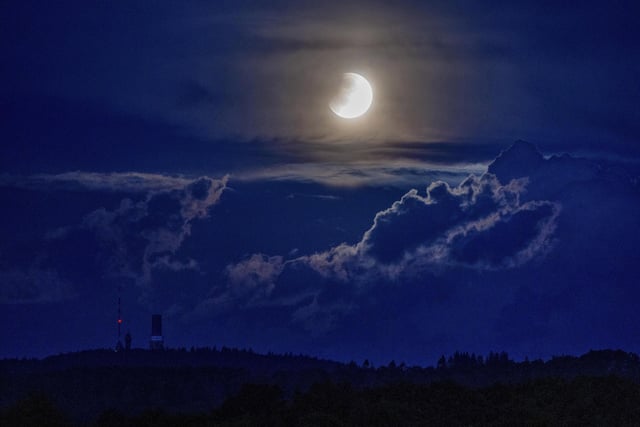 A lunar eclipse begins as the full moon sets over the hills of the Taunus mountains near Frankfurt, Germany, Monday, May 16, 2022. (AP Photo/Michael Probst)
