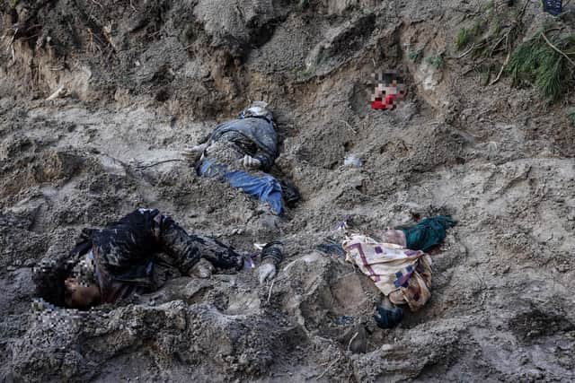 Bodies are seen in a mass grave in Bucha, northwest of the Ukrainian capital Kyiv on April 4, 2022. - The EU said on April 4, 2022, it is urgently discussing a new round of sanctions on Russia as it condemned "atrocities" reported in Ukrainian towns that have been occupied by Moscow's troops. Russia invaded Ukraine on February 24, 2022. (Photo by RONALDO SCHEMIDT / AFP)