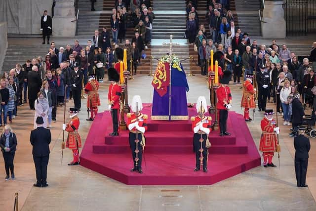 Members of the public file past the coffin of Queen Elizabeth II, draped in the Royal Standard with the Imperial State Crown and the Sovereign's orb and sceptre, lying in state on the catafalque in Westminster Hall