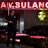 An armed police officer guards the ambulance entrance to the Central Maine Medical Center in Lewiston, Maine. A massive manhunt was under way for a gunman who opened fire in a bowling alley and bar.
