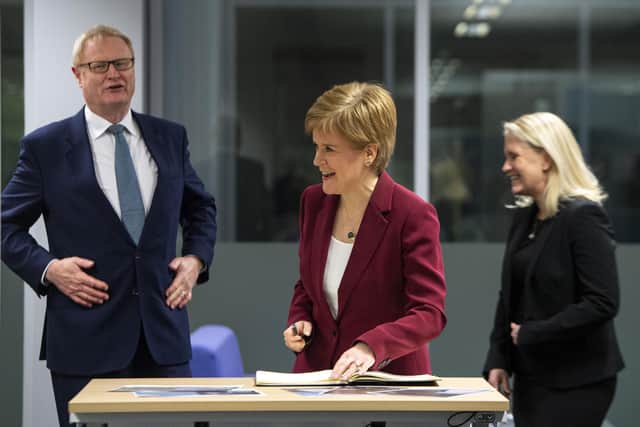 Scotland's First Minister Nicola Sturgeon (C) flanked by former Scottish National Investment Bank CEO Eilidh Mactaggart (R) and chair Willie Watt signs a visitors book at the bank's official launch at their headquarters on November 19, 2020 in Edinburgh, Scotland. (Photo by Andy Buchanan - WPA Pool/Getty Images)