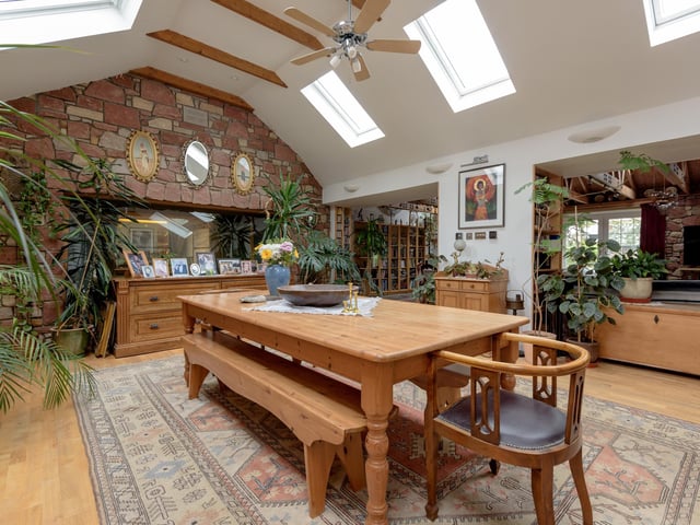 The light-filled dining area has a vaulted ceiling with exposed roof beams and a wooden floor