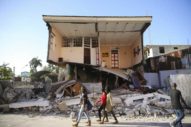 People walk past a home destroyed by the earthquake in Les Cayes, Haiti. Picture: AP Photo/Joseph Odelyn