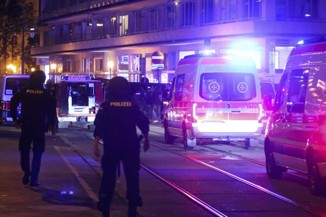 A police officers walk near ambulances at the scene after gunshots were heard, in Vienna.