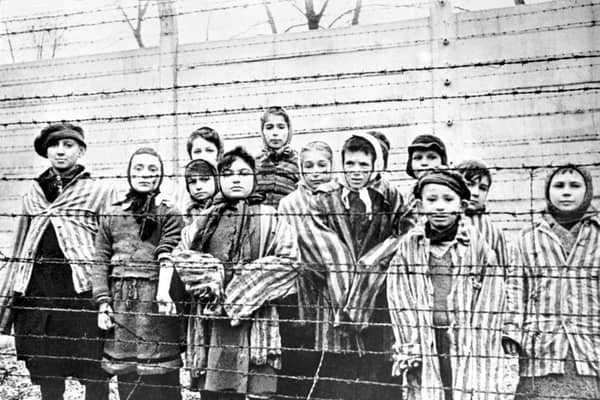 A group of child survivors behind a barbed wire fence at the Nazi concentration camp at Auschwitz-Birkenau in southern Poland, on the day of the camp’s liberation by the Red Army, 27th January 1945 (Picture: Alexander Vorontsov/Galerie Bilderwelt/Getty Images)