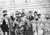 A group of child survivors behind a barbed wire fence at the Nazi concentration camp at Auschwitz-Birkenau in southern Poland, on the day of the camp’s liberation by the Red Army, 27th January 1945 (Picture: Alexander Vorontsov/Galerie Bilderwelt/Getty Images)